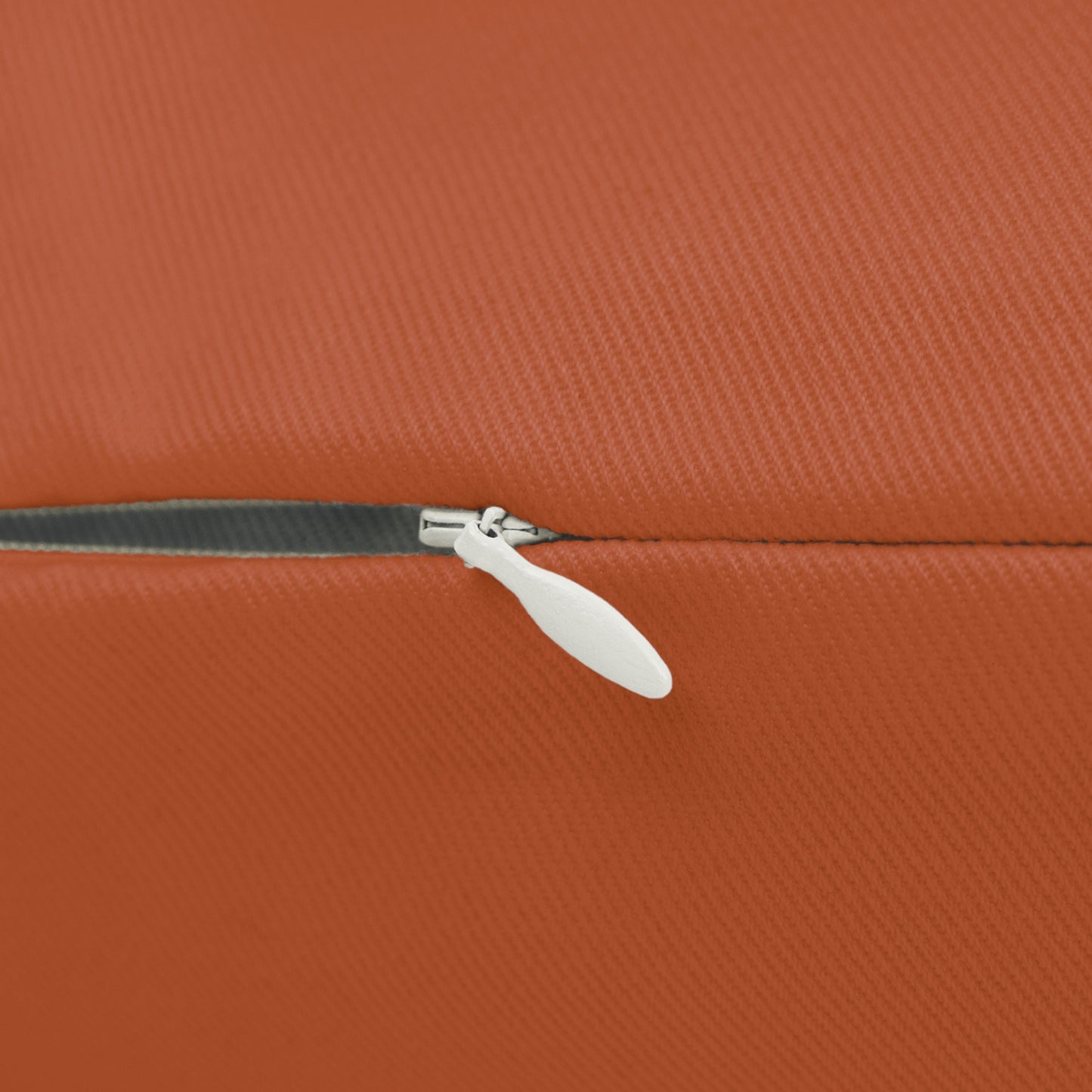 Close-up of a white zipper on an orange textured surface