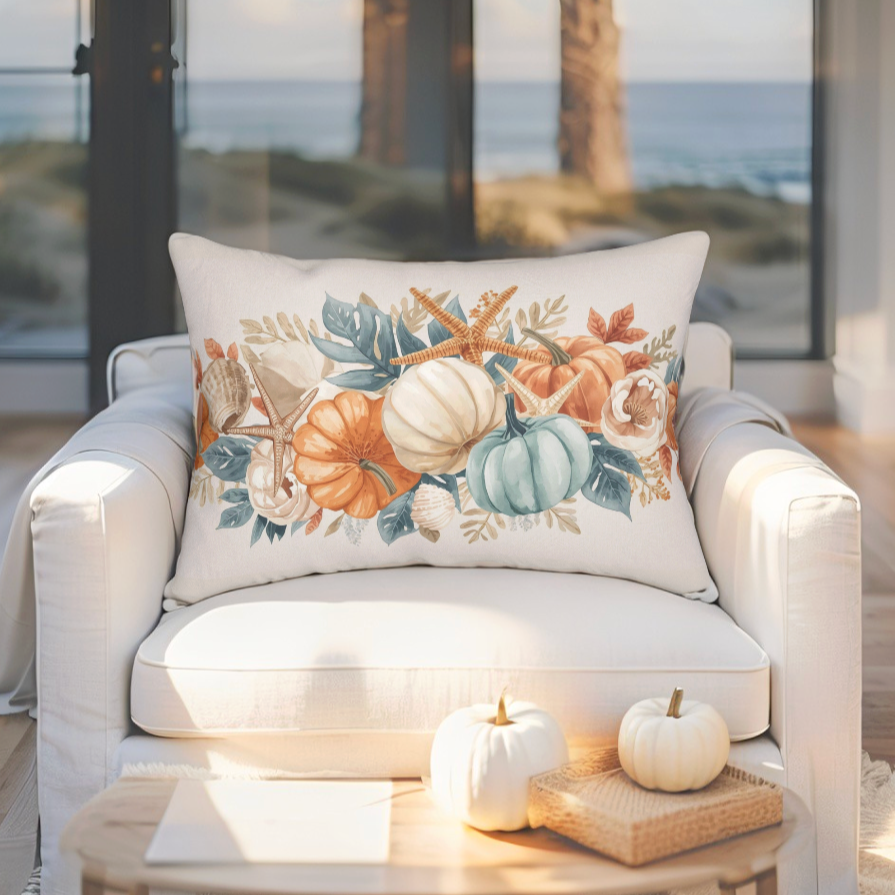 Decorative pillow with pumpkins, seashells, and leaves on a white armchair in a room with large windows.