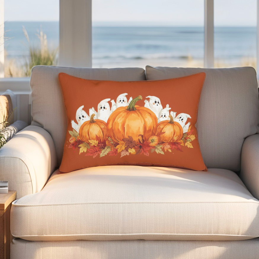 Decorative pillow with pumpkins and ghosts on a beige sofa by a window with a view of the ocean.