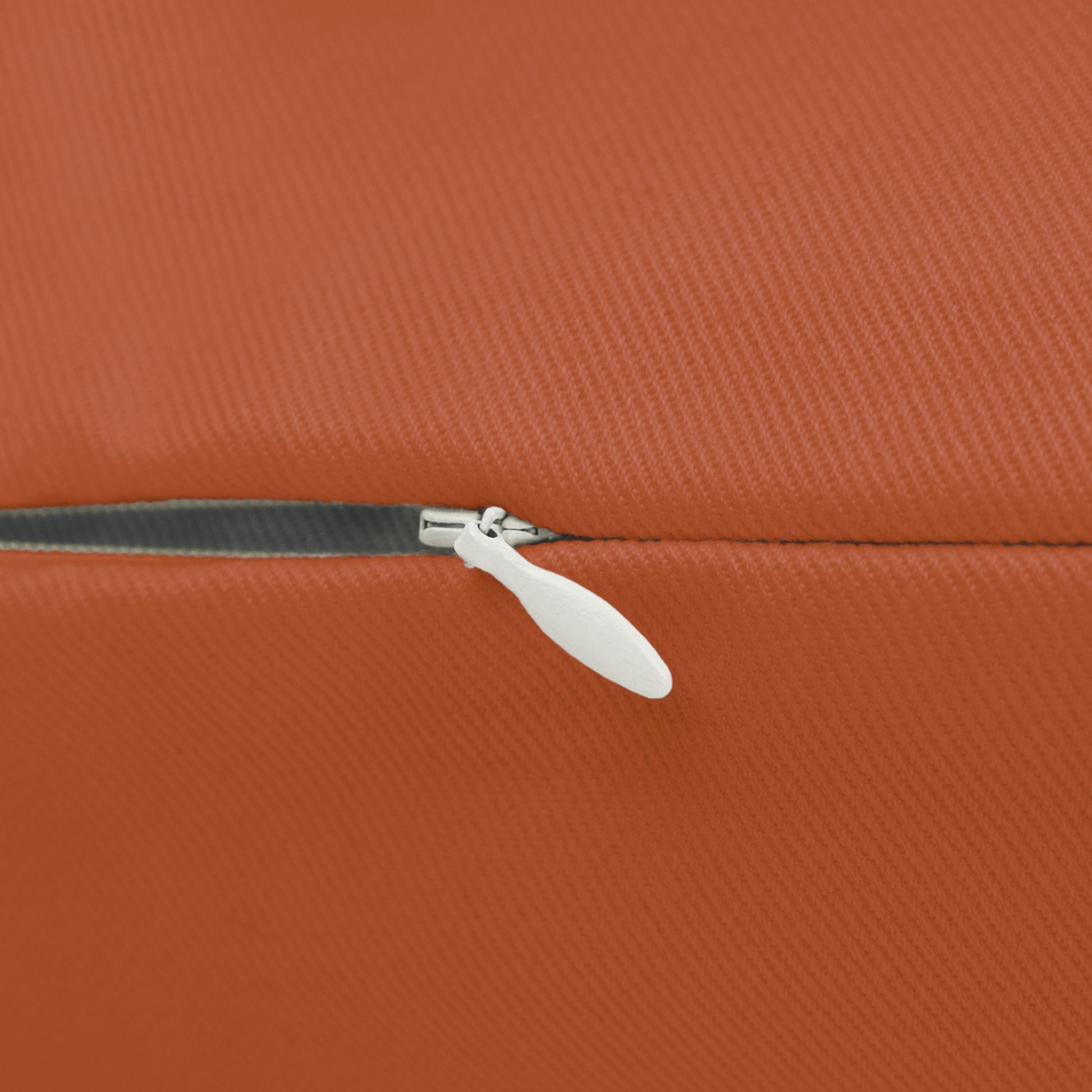 Close-up of a white zipper on an orange textured surface