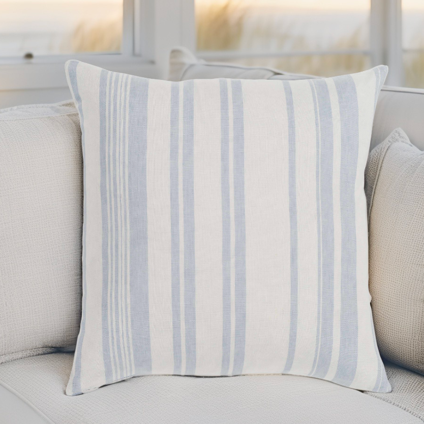 Coastal farmhouse pillow adding soft blue tones to a bright seaside living room.