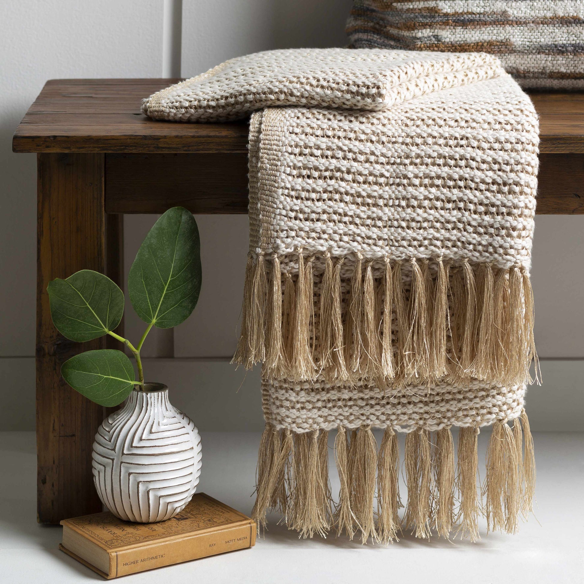 Soft knitted tan throw blanket with fringe, perfect for modern coastal or boho interiors