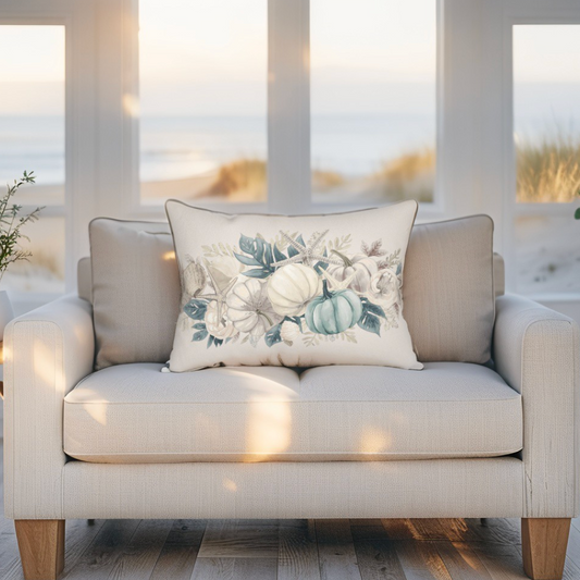 Decorative pillow with floral and pumpkin design on a beige sofa in a room with large windows. Coastal Fall Pillow