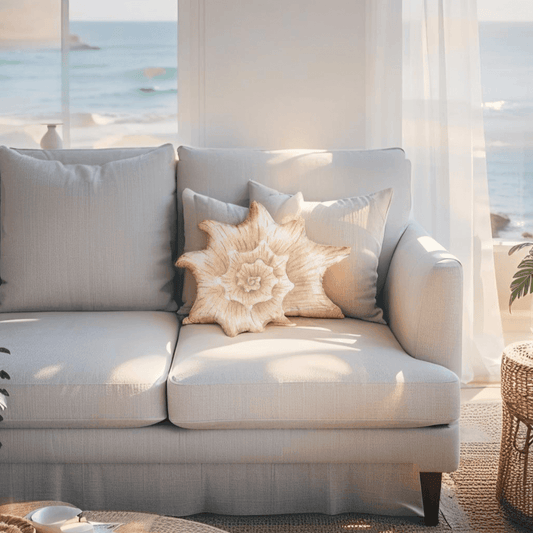 Blush seashell pillow styled in a coastal bedroom setting on a white duvet