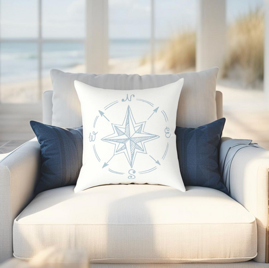 Coastal-style pillow featuring a compass motif in light blue, ideal for beach house and nautcial decor.