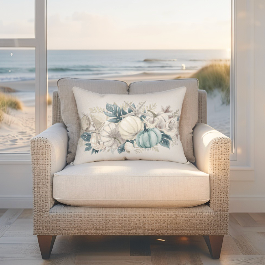 Beige armchair with a decorative pillow featuring floral and pumpkin design, set against a beach window view.