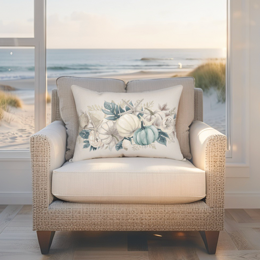 Beige armchair with a decorative pillow featuring floral and pumpkin design, set against a beach window view.