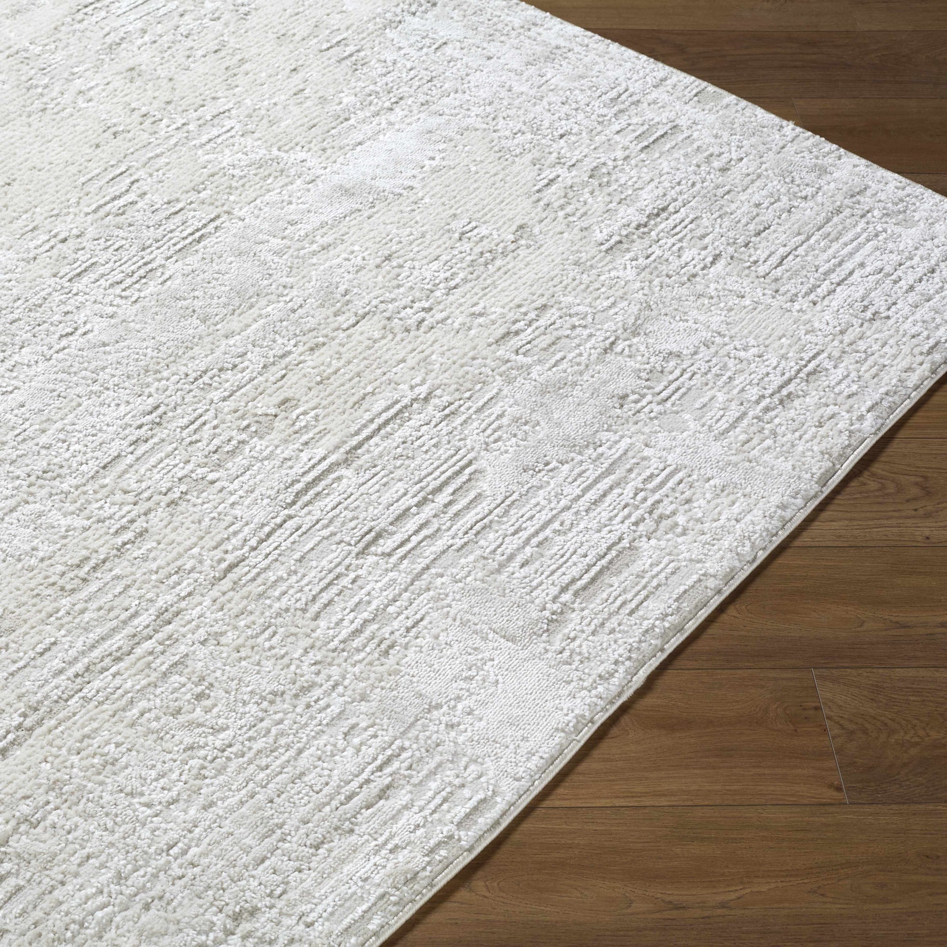 A coastal farmhouse area rug in ivory, cream, and light gray tones styled in a bright beach house living room.