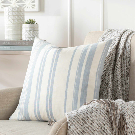 Pale blue striped throw pillow on a white linen sofa in a coastal farmhouse living room.