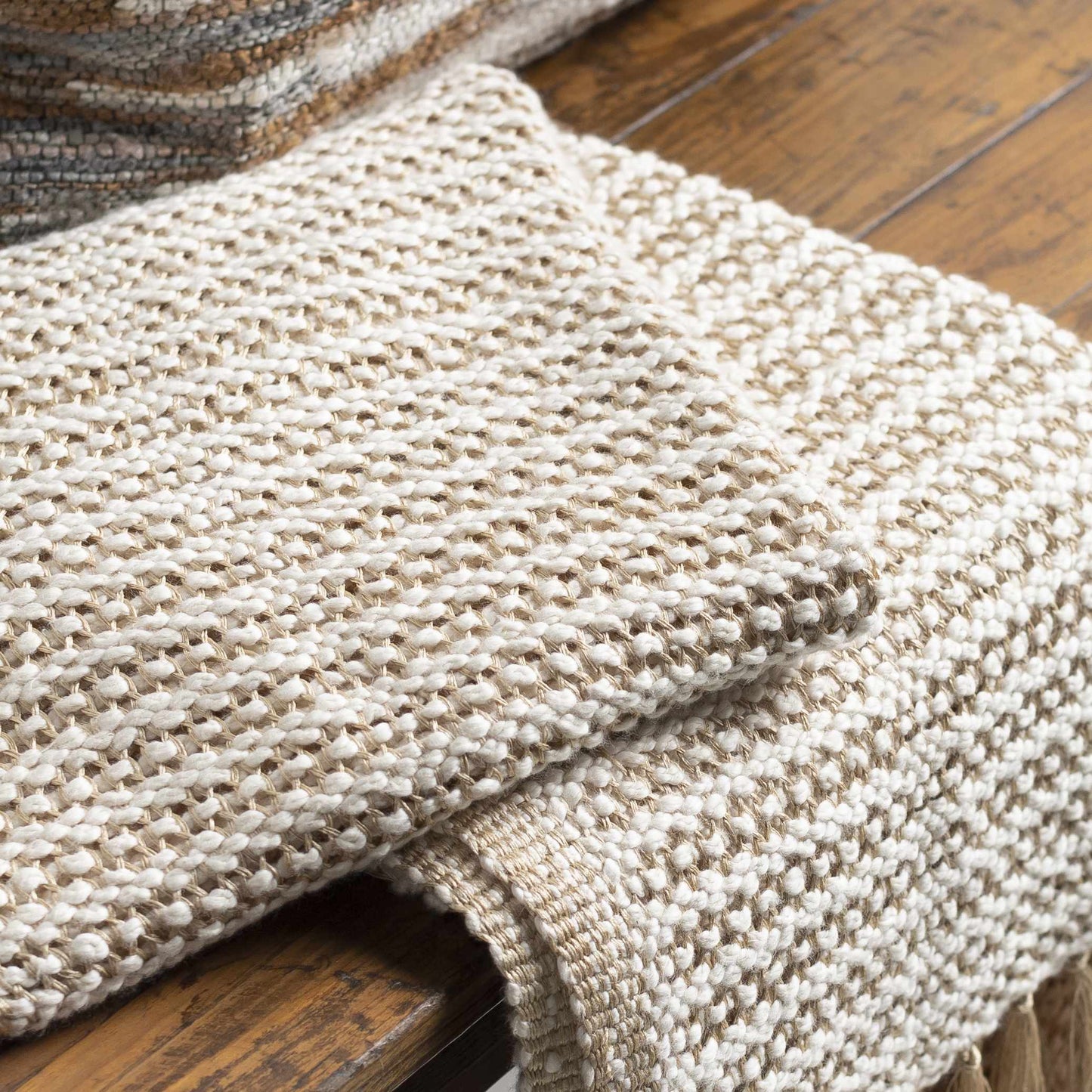 Soft knitted tan throw blanket with fringe, perfect for modern coastal or boho interiors