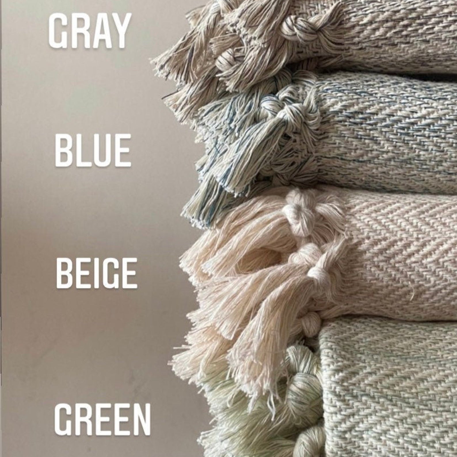 Stack of textured blankets in gray, blue, beige, and green on a neutral background.