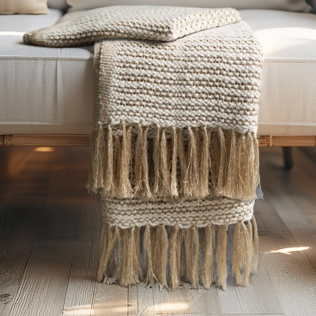 Soft tan knitted throw with fringe creating a warm and airy coastal look.